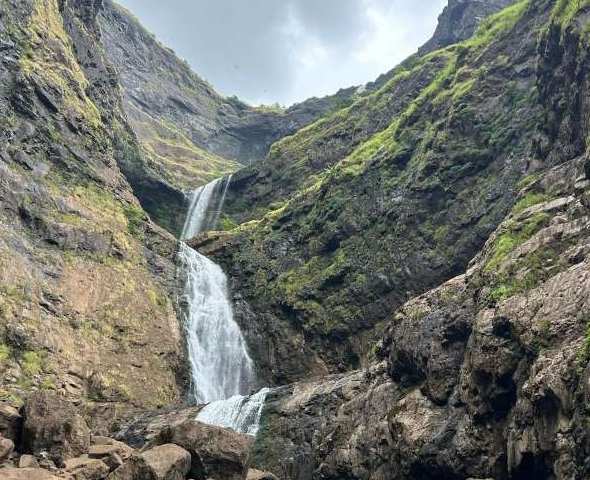 A trekker pointing at Kalu waterfall in Malshej Ghat