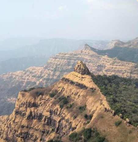 A trekker with a backpack looking out over the hills